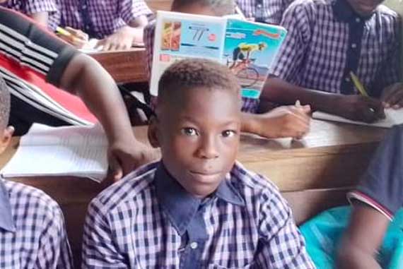 Eine Gruppe von Kindern sitzt in einem Klassenzimmer und hört aufmerksam dem Lehrer zu.