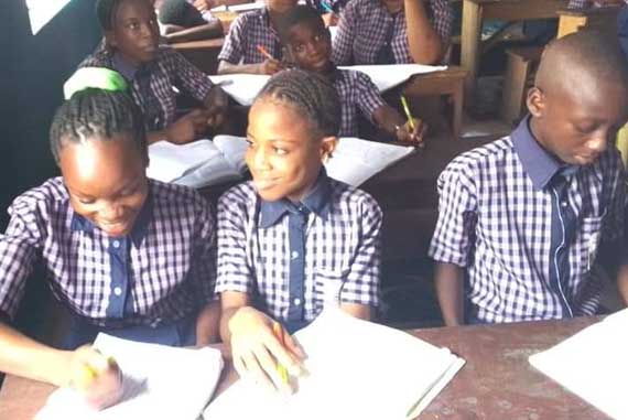 Eine Gruppe von Kindern sitzt an Schreibtischen in einem Klassenzimmer und lernt gemeinsam.